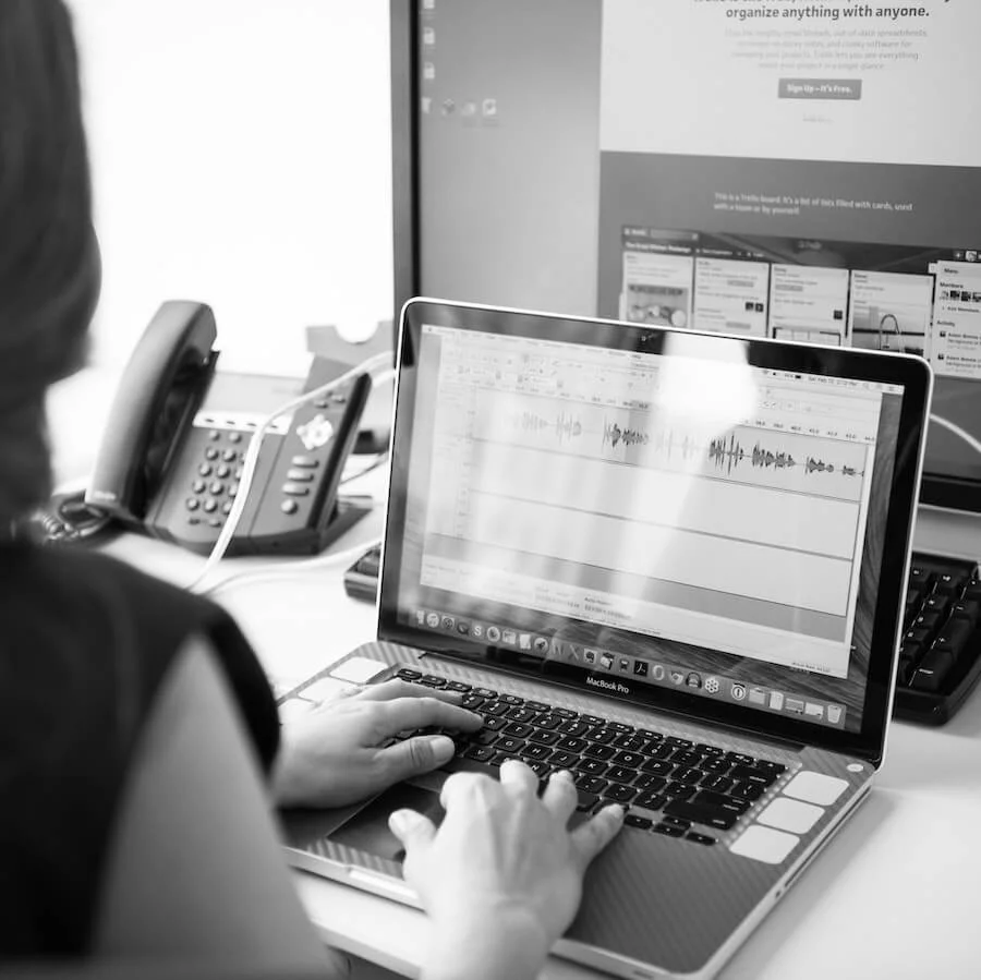 Black and white photo of a woman sitting at a desk working on a laptop