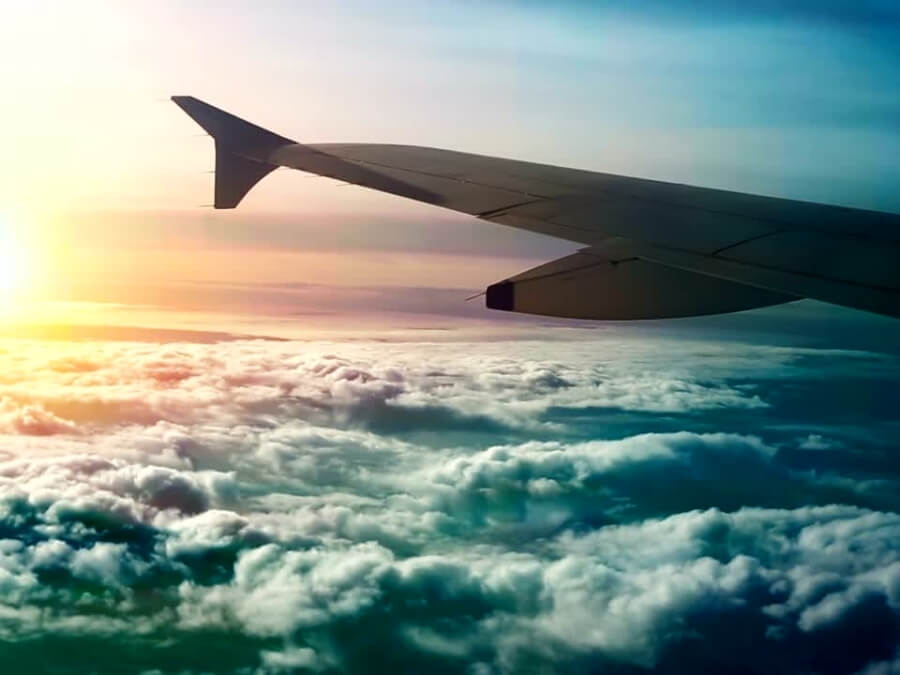 Shot from inside an airplane looking a a wing and the clouds, at sunset.