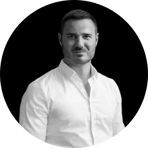 A smiling man with short, dark hair wearing a white shirt.